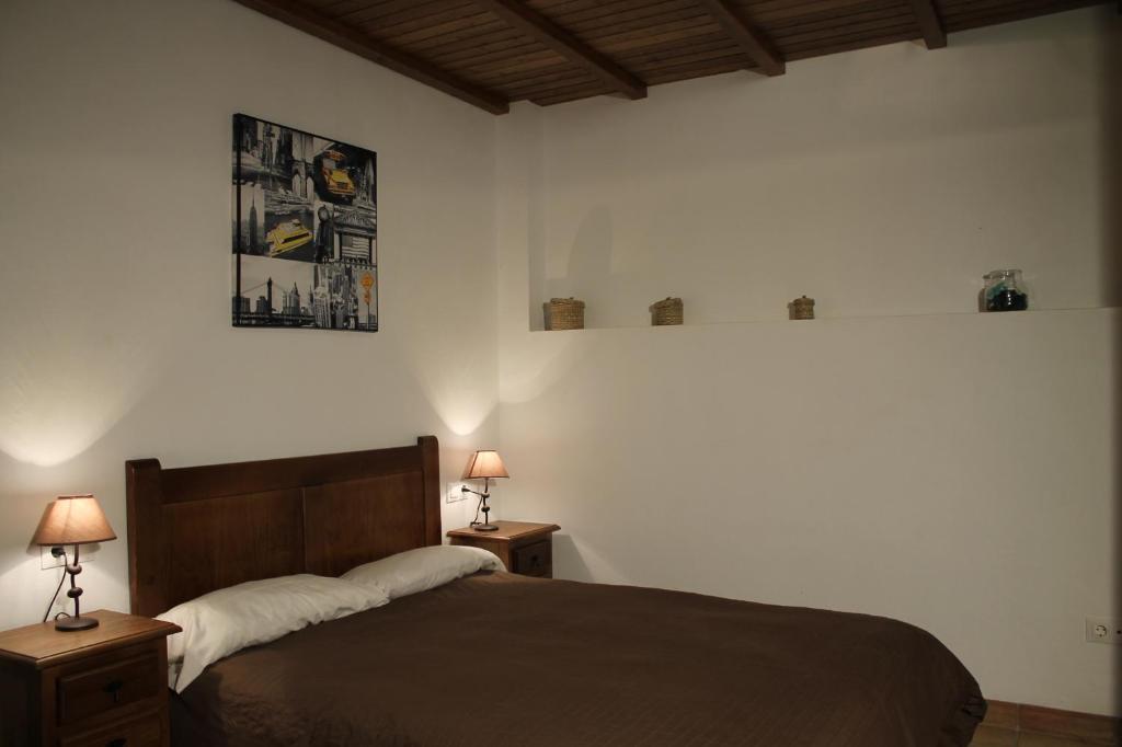 1 dormitorio con 1 cama con 2 mesitas de noche y 2 lámparas en Apartamentos Real Fábrica Hojalata, en Júzcar