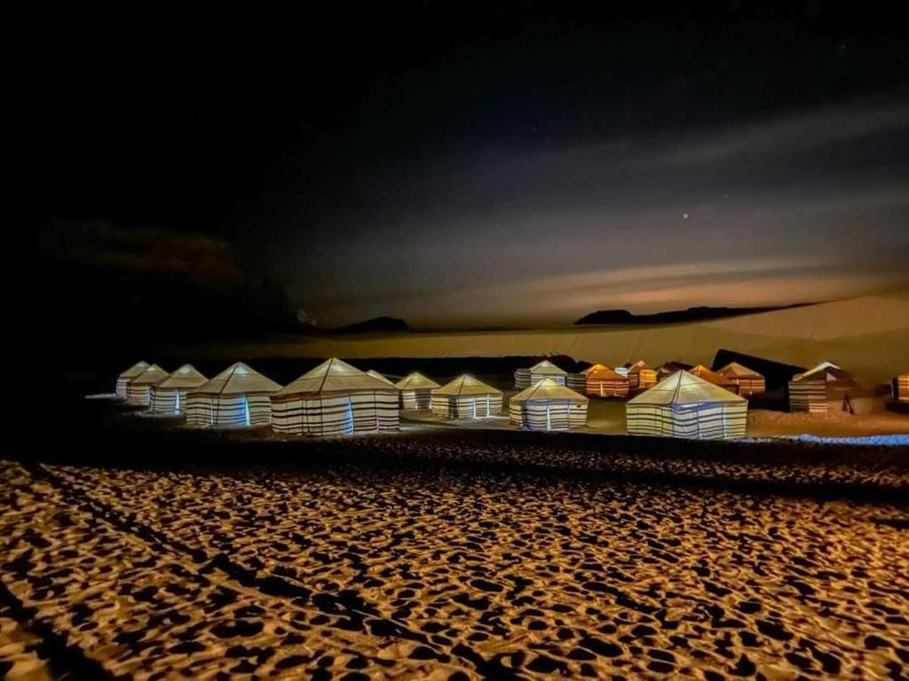 a row of beach huts on the beach at night at Qusoor elarab Camp in Qaryat Ḩātim aţ Ţāʼī