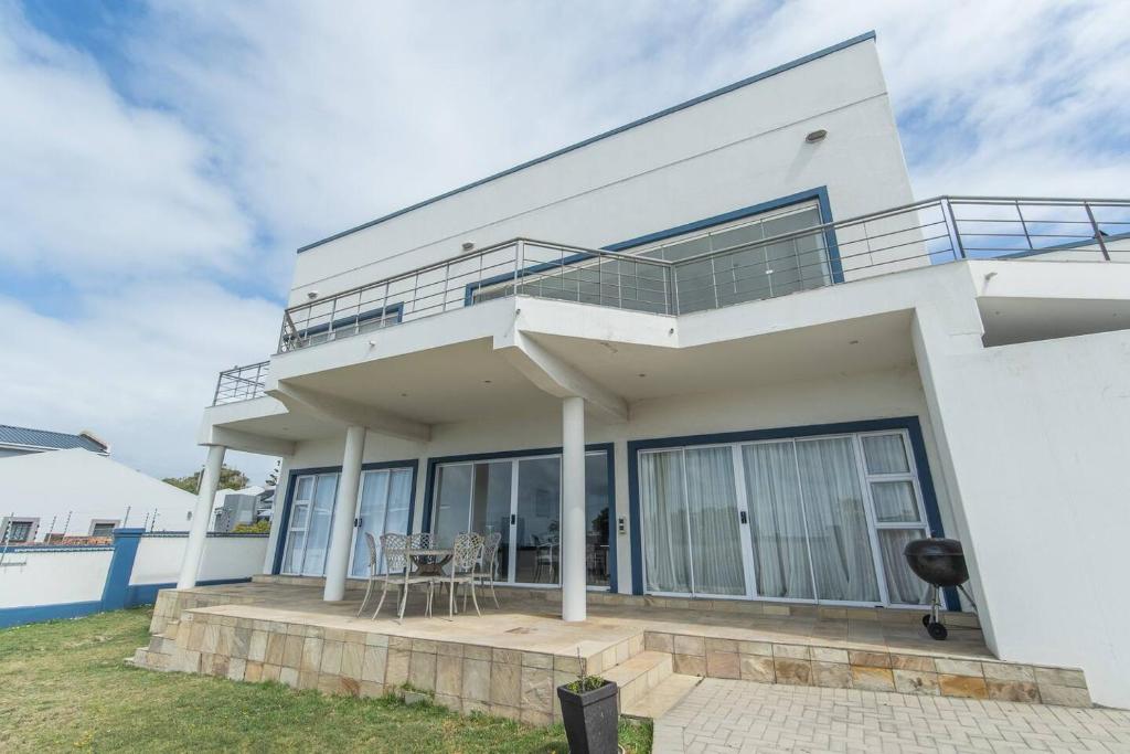 een wit huis met een balkon en een patio bij The Nautical Nook in Gqeberha