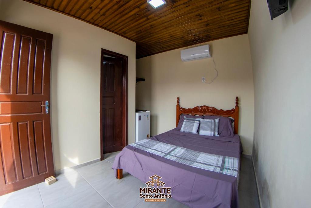 a bedroom with a bed with a purple comforter at Mirante Santo Antônio Pousada e Camping in Laguna