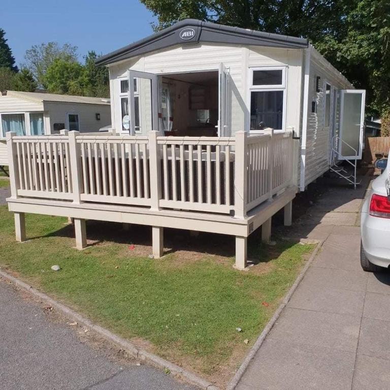a white house with a porch and a fence at Kiln Park in Tenby