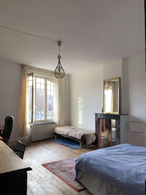 une chambre avec un lit, une table et un miroir dans l'établissement Maison Bourgeoise années 50, à Haybes