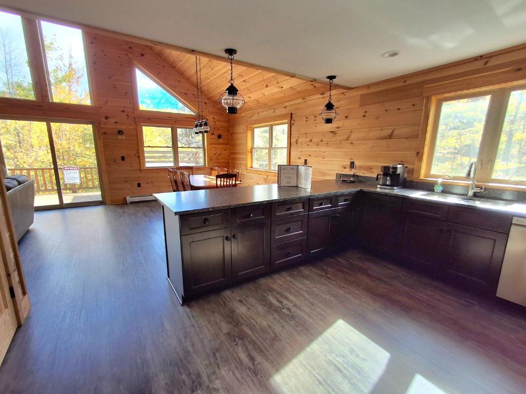 a large kitchen with wooden walls and wooden floors at Scoot Cabin - Dogs Welcome! in Carrabassett