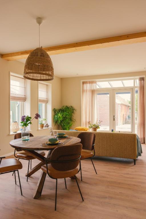 a living room with a table and chairs and a couch at B&B De Korenbloem in Noordbroek