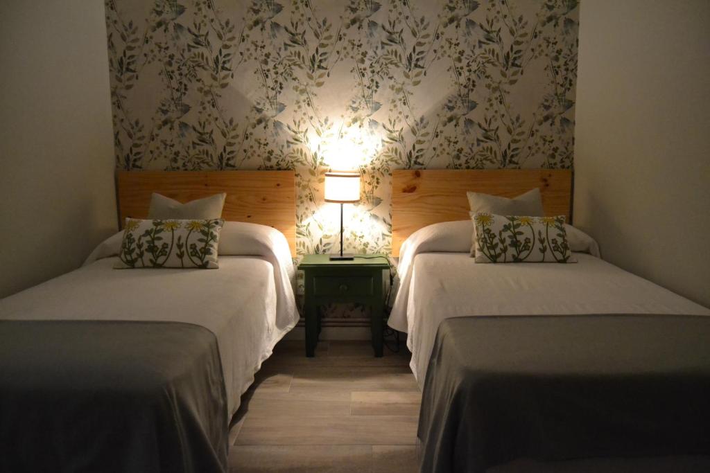 a hotel room with two beds and a lamp at El Balcón de Gredos in Candeleda