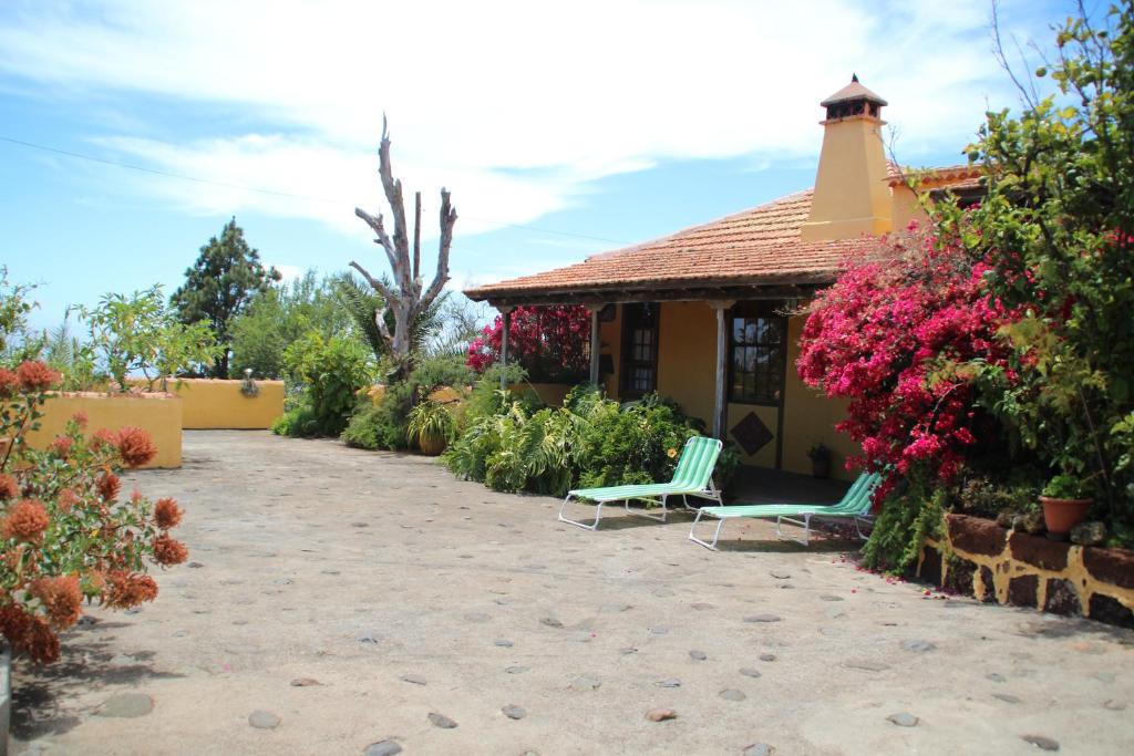 a house with two chairs and flowers in a yard at Casas Rurales Los Marantes in Puntagorda