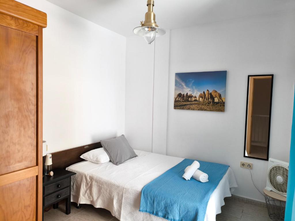 a bedroom with a bed with a blue blanket at Acogedoras Habitaciones Privadas zona Costera Wifi in Morro del Jable