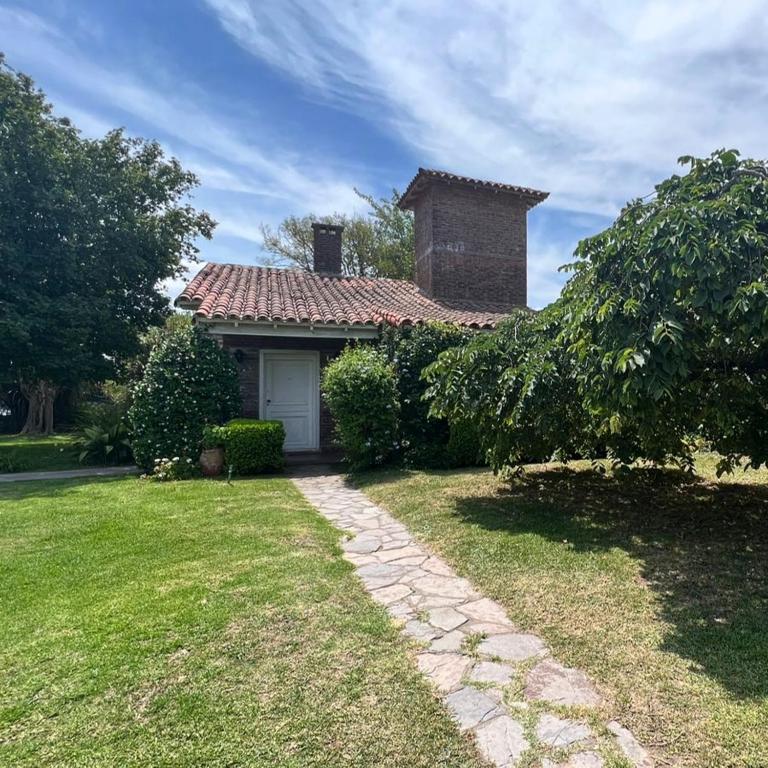 a house with a white door and a grass yard at Casita de Capilla como Hotel in Capilla del Señor