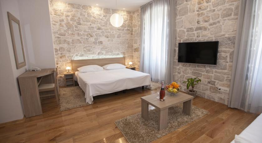 a bedroom with a white bed and a stone wall at Tifani Luxury Rooms 2 in Split