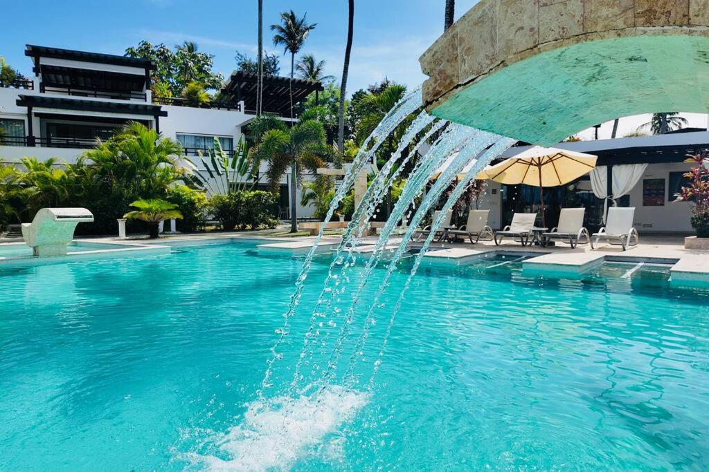 a fountain in the middle of a swimming pool at Aligio Beachfront Resort & Spa in Las Terrenas