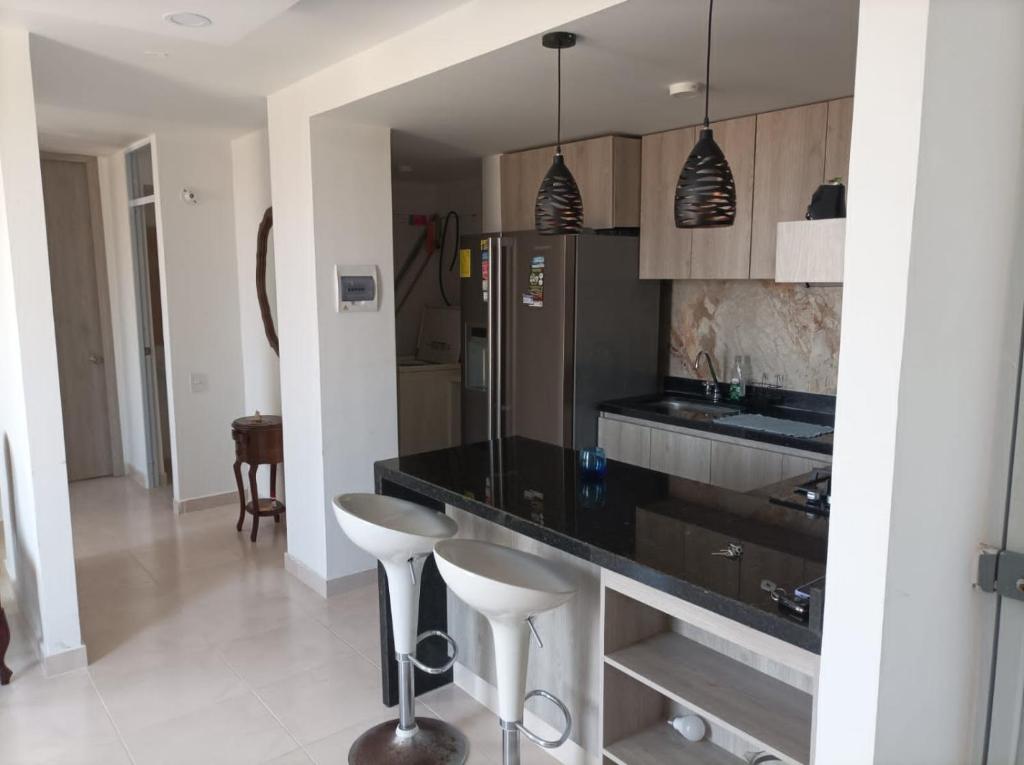 a kitchen with a black counter and stools in it at apartamento Amazilia en alameda del rio in Barranquilla