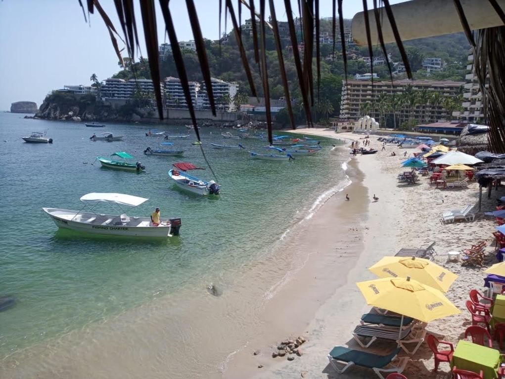 une plage avec des parasols et des bateaux dans l'eau dans l'établissement Casa maleni 2 en mismaloya, à Puerto Vallarta