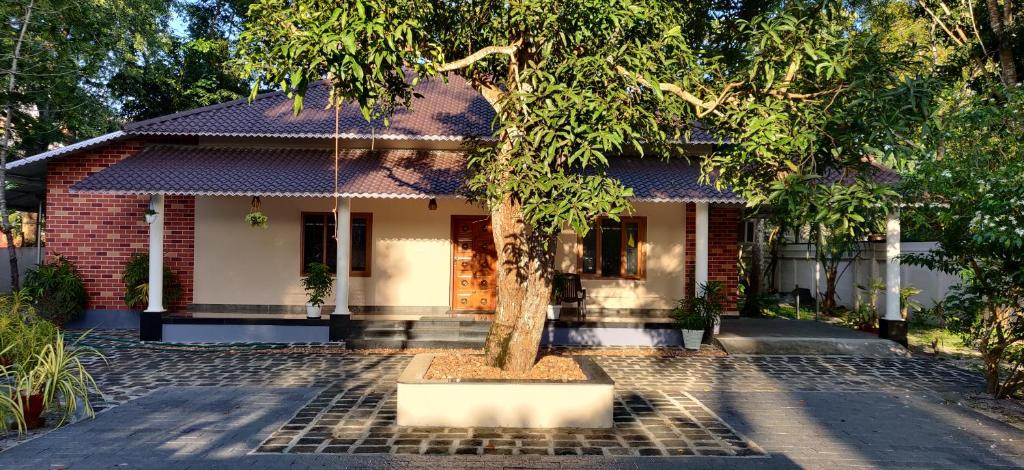 a house with a tree in front of it at Angel Homestay Paravoor in Alleppey