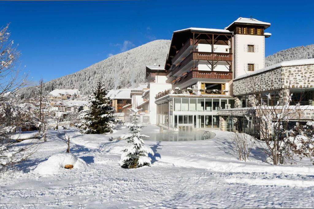 a building in the snow in front of a mountain at Romantik Hotel Post in Nova Levante