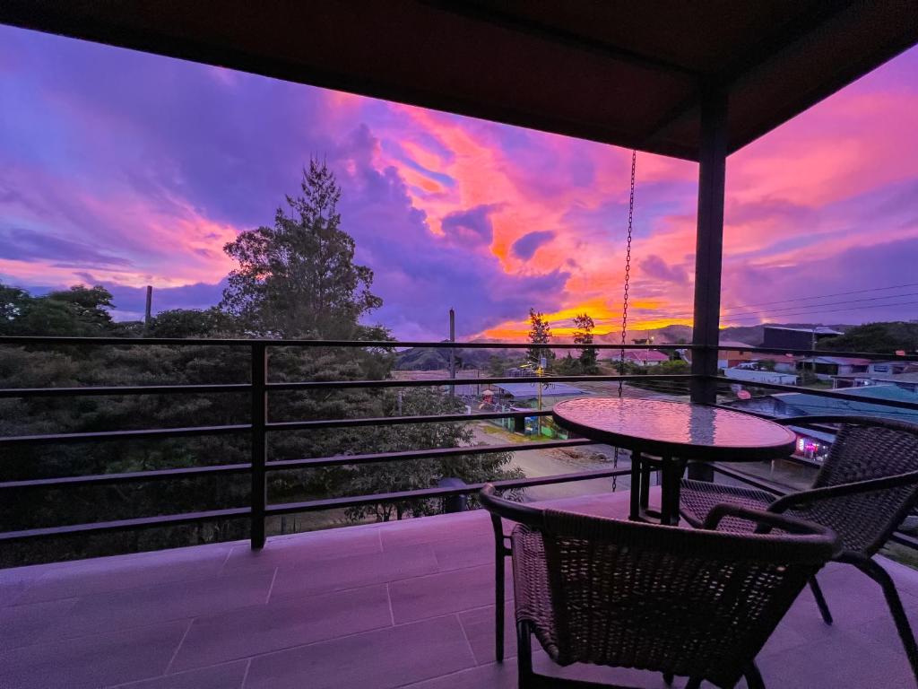 a table and chairs on a balcony with a sunset at Monstera Apartments Monteverde in Monteverde Costa Rica