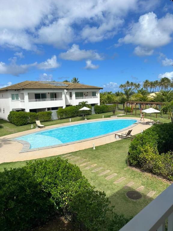 a large swimming pool in front of a house at Apartamento 03 suítes - Tree Bies Beach Resort - Praia de Subaúma in Entre Rios