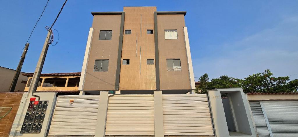 un edificio alto con una puerta delante de una valla en Apartamento Temporada Barra-Vento, en Guriri