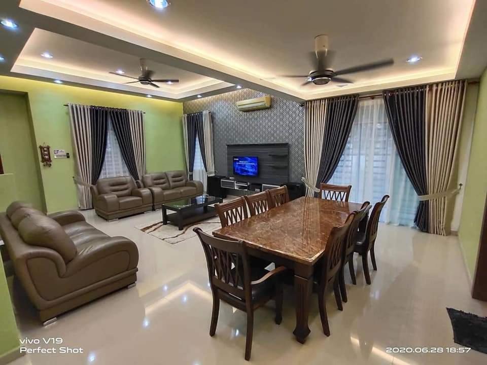 a living room with a table and chairs and a couch at Homestay Teratak Zuarie Segamat in Segamat