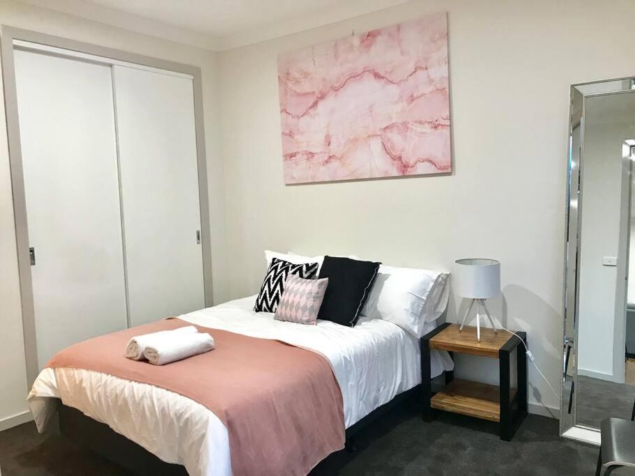 - une chambre avec un lit orné d'une peinture rose sur le mur dans l'établissement D112 Braybrook Central Stay-Great Getaway, à Braybrook