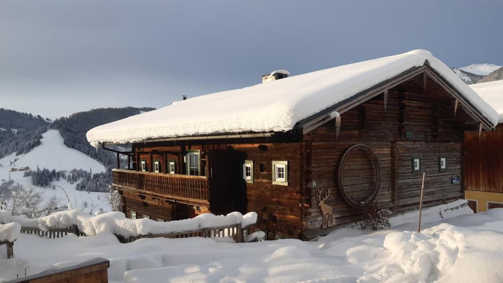 una cabaña de troncos con nieve en el techo en Almhütte Brandgut, en Mühlbach am Hochkönig