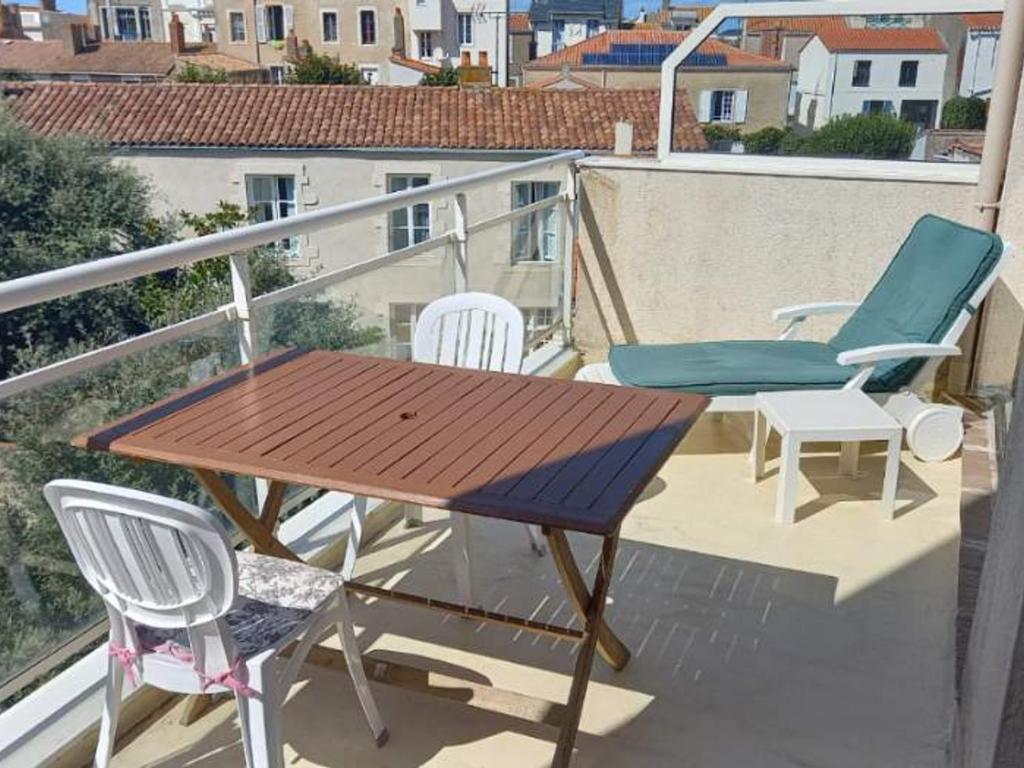 une table et des chaises en bois sur un balcon dans l'établissement Duplex 4 pers, à 150m de la plage avec garage privé - FR-1-197-574, à Les Sables-dʼOlonne