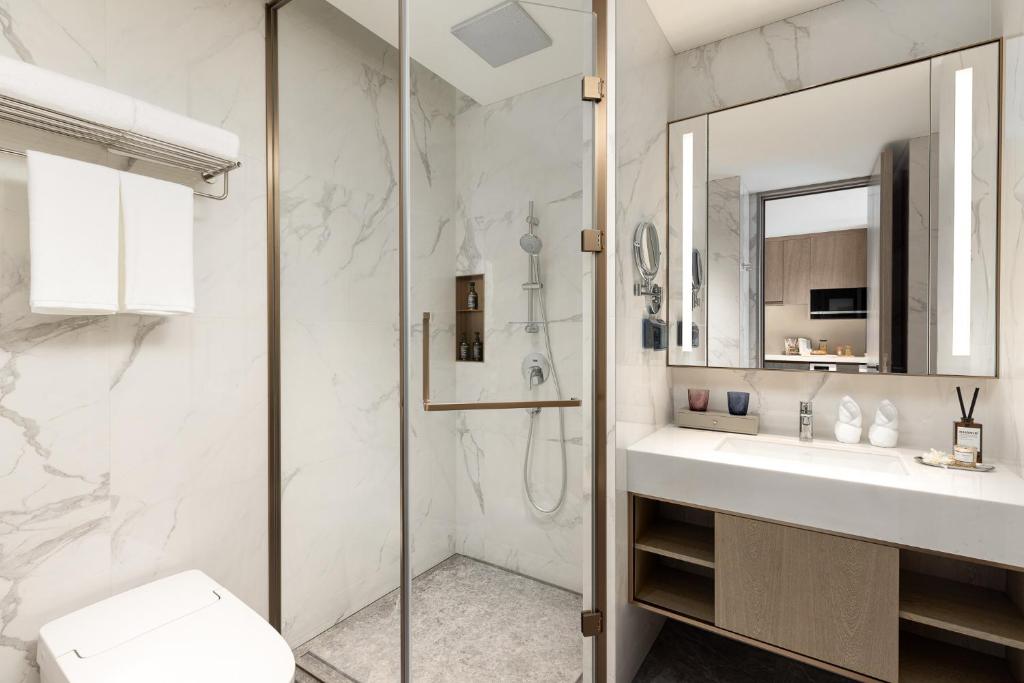 a bathroom with a shower and a sink and a toilet at Somerset QPlex Shenzhen in Shenzhen