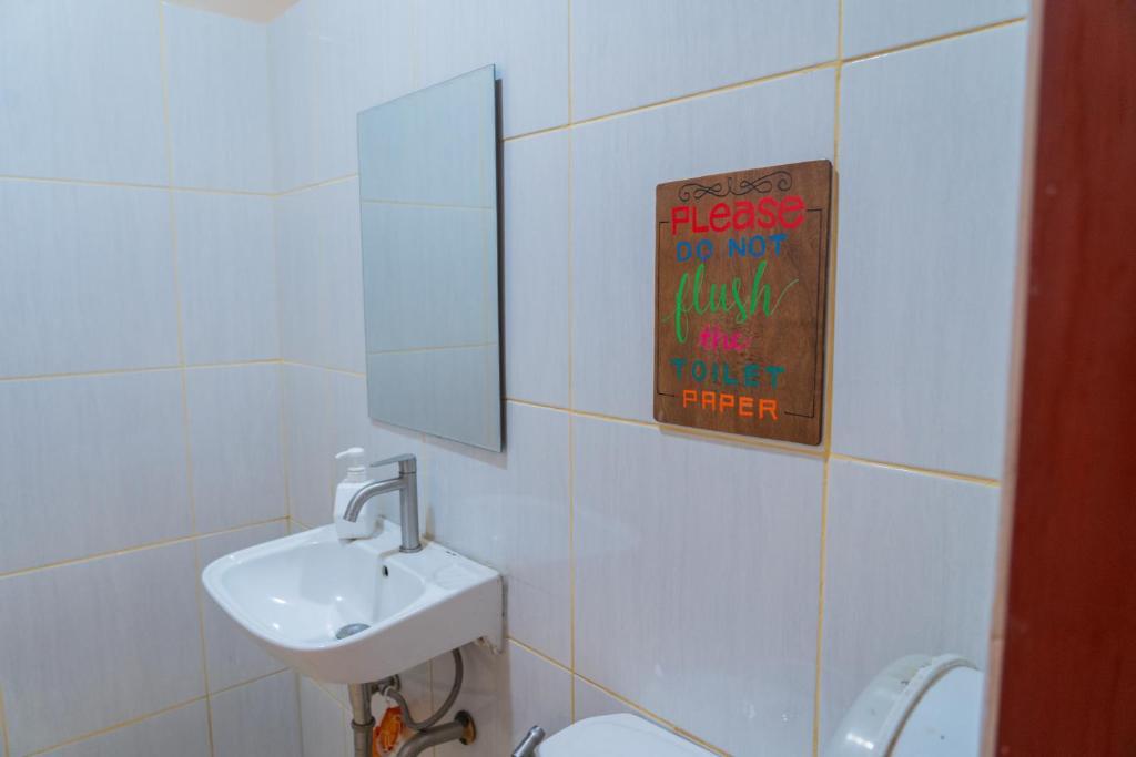 a bathroom with a toilet and a sink and a sign at CocoRico Hostel in San Vicente