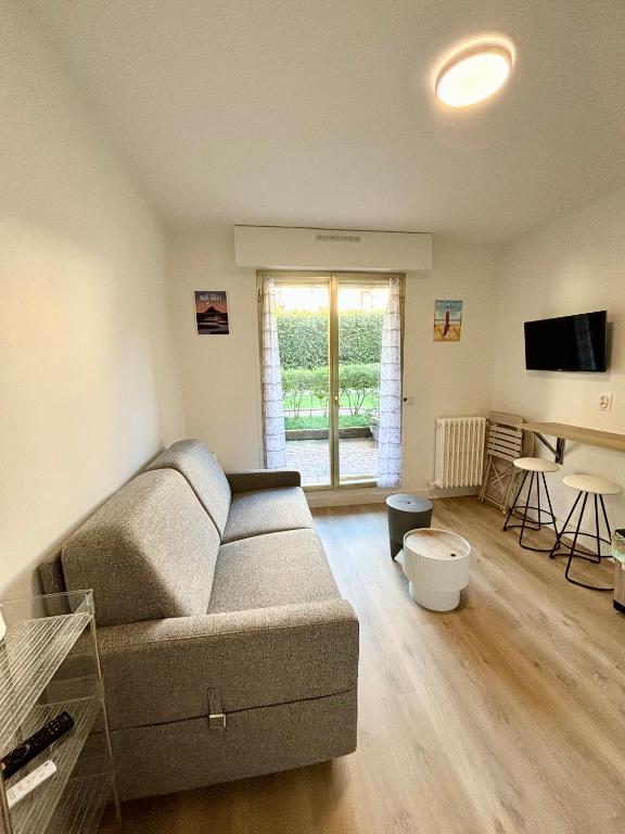 un salon avec un canapé et une table dans l'établissement Studio en rez de jardin DEAUVILLE CENTRE et Plage, à Deauville