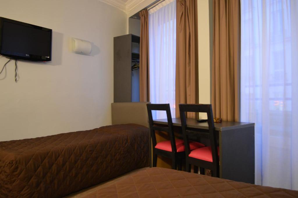 パリにあるオテル アレティのベッド、デスク、椅子が備わるホテルルームです。
