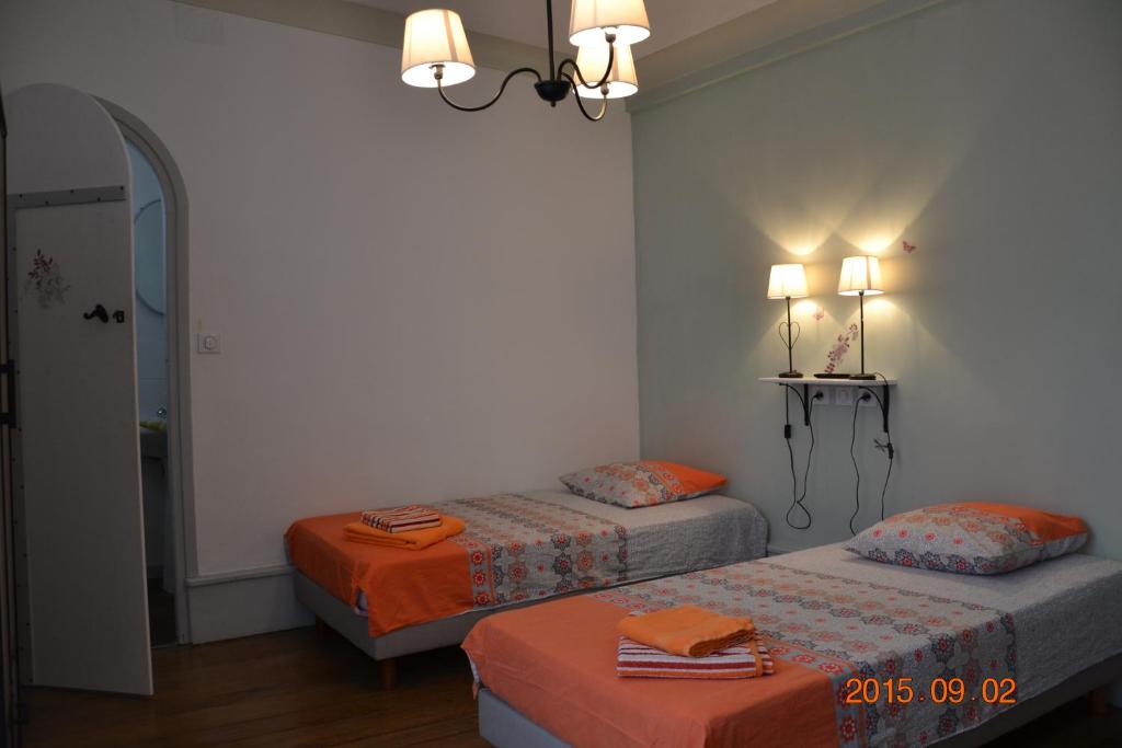 a bedroom with two beds and a chandelier at Mère Elvira in Lourdes