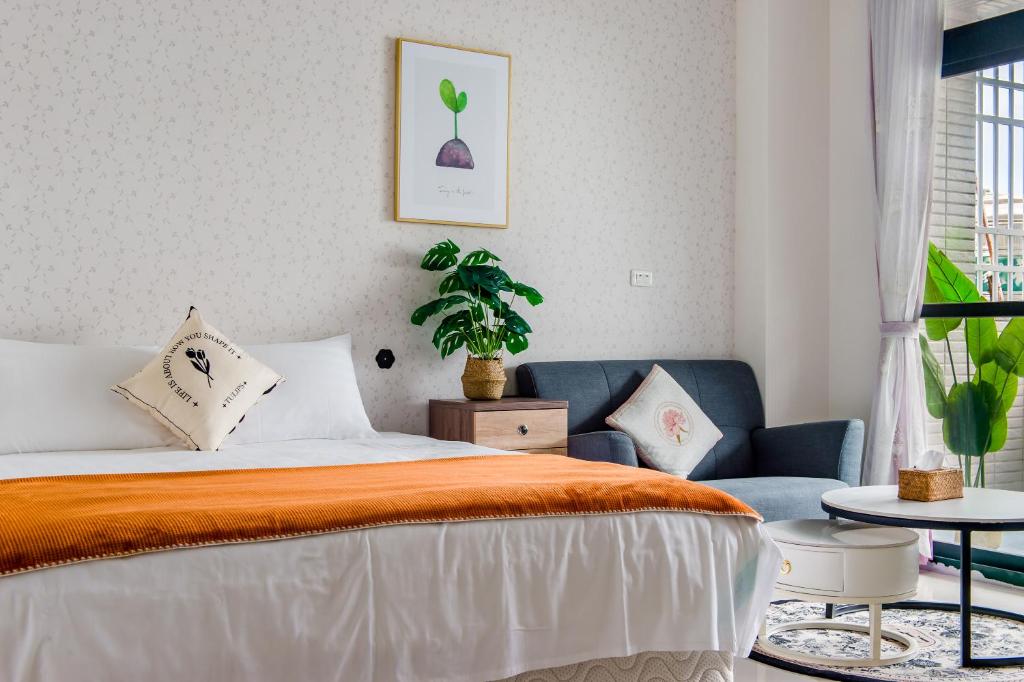 ein Schlafzimmer mit einem Bett und einem Sofa und einer Pflanze in der Unterkunft Sakura B&B in Taitung