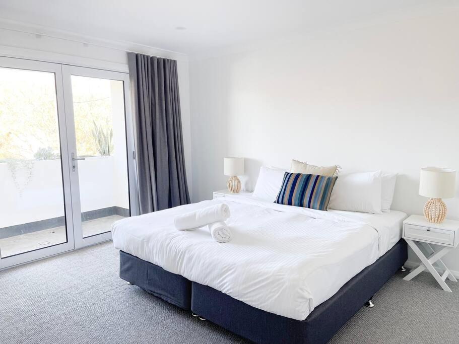 a white bedroom with a large bed and a window at Modern Central Retreat 1 in Wagga Wagga