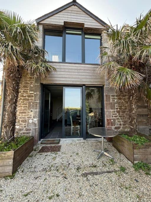 une maison en briques avec une table devant elle dans l'établissement Les Palmiers, à Regnéville-sur-Mer