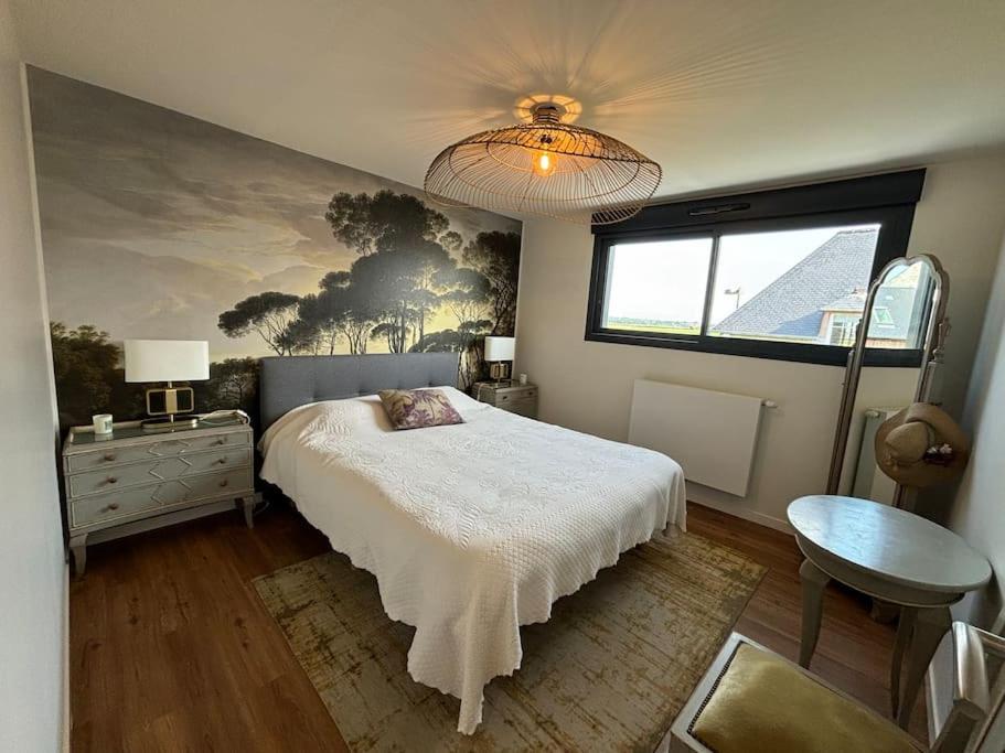 ein Schlafzimmer mit einem Bett und einem Gemälde an der Wand in der Unterkunft Les Palmiers in Regnéville-sur-Mer