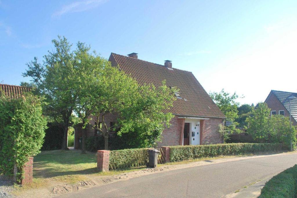 a brick house with a hedge in front of a street at Gästehaus Rohde in Rothenhaus