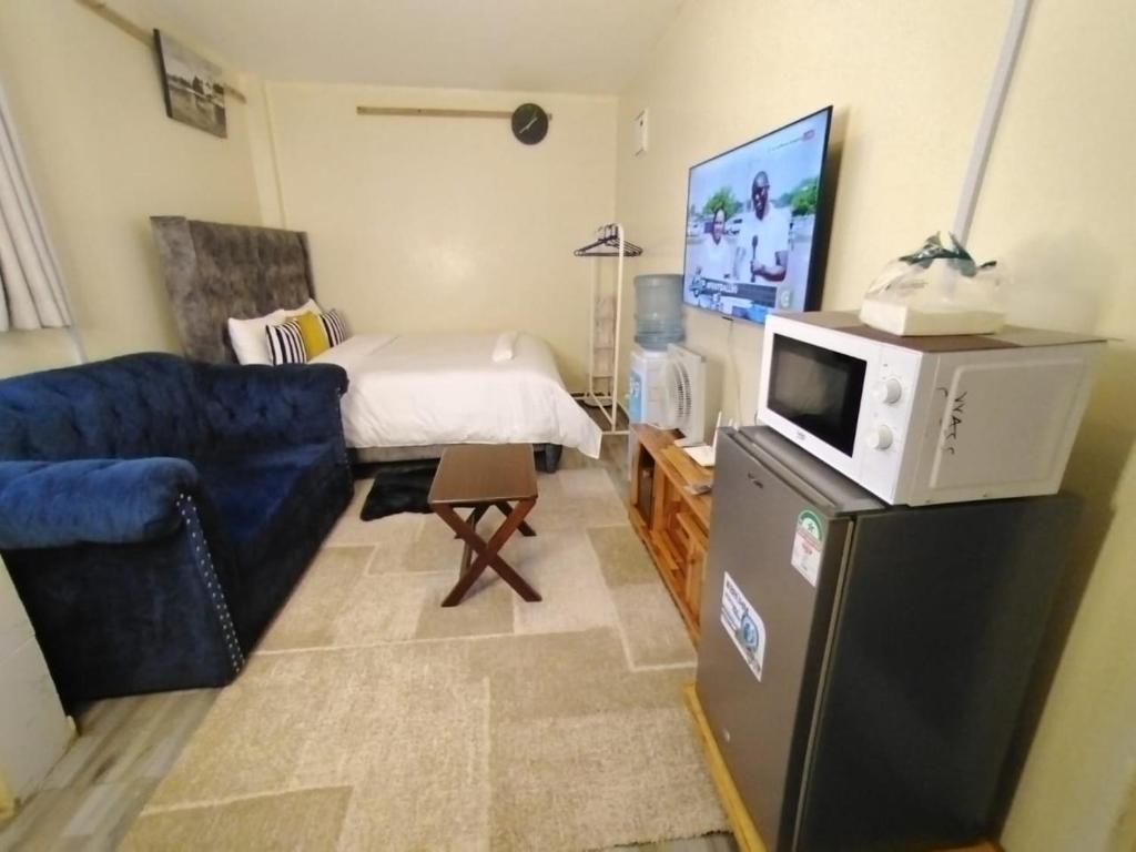 a living room with a blue couch and a tv at Marvel Homes-Kivaa,Studio in Mavuria