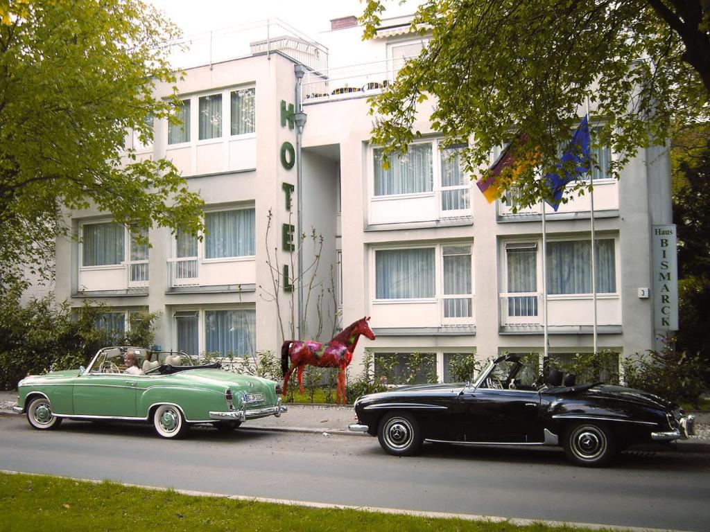 zwei alte Autos, die vor einem Gebäude geparkt sind in der Unterkunft Hotel Haus Bismarck in Berlin