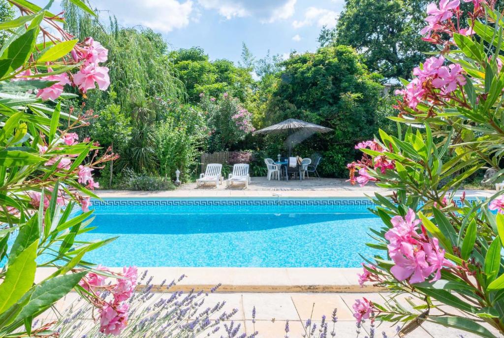 - une piscine dans une cour ornée de fleurs roses dans l'établissement 30ciga, à Saint-Brès