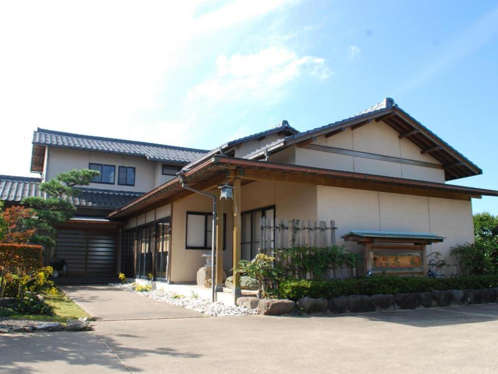 a japanese house with a gate and a driveway at Minshuku Shima in Kaga