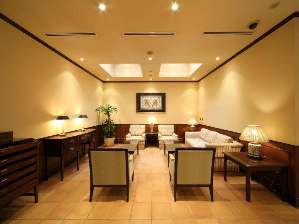 Una sala de espera con sofás, mesas y sillas. en Hotel Harvest In Yonago, en Bakurōmachi