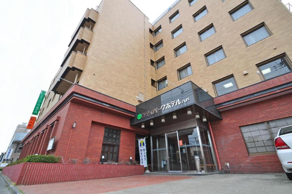 a red brick building with a sign for a hotel at City Park Hotel Hachinohe in Minatomachi