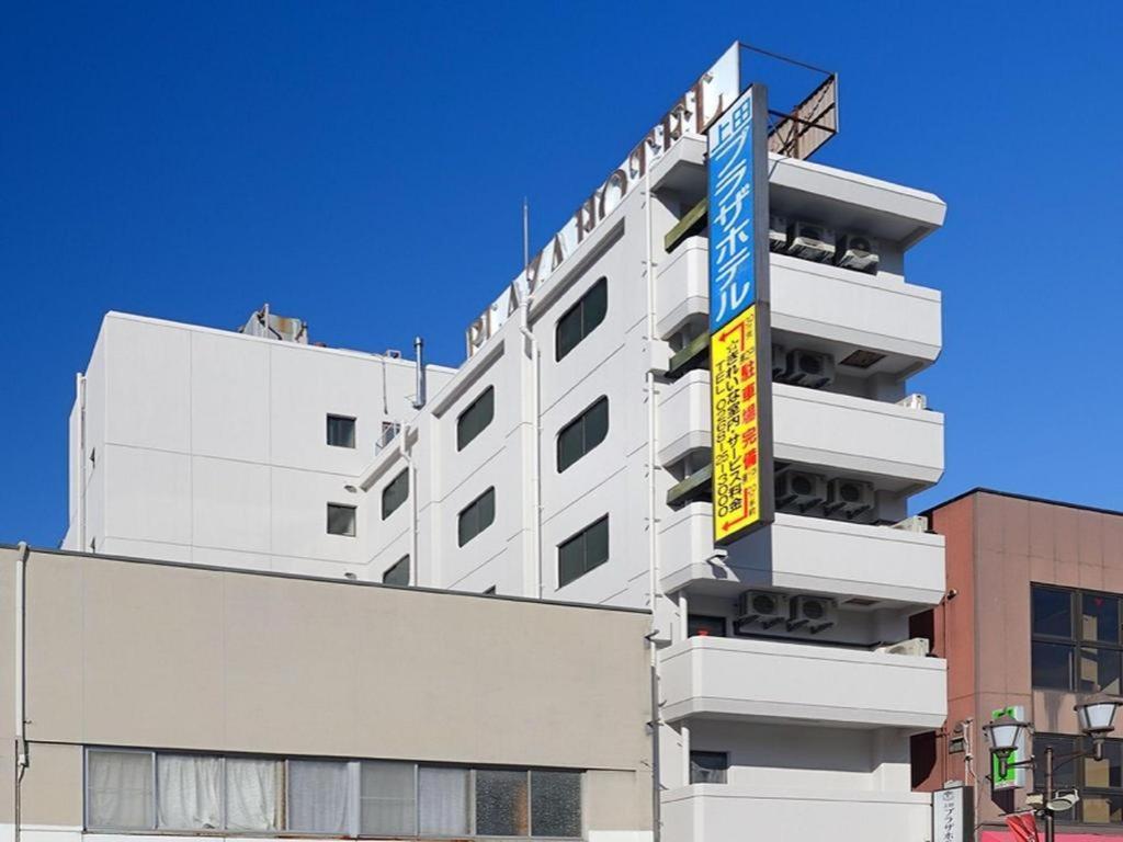 上田市Ueda Plaza Hotel的一栋白色建筑，侧面有一块招牌