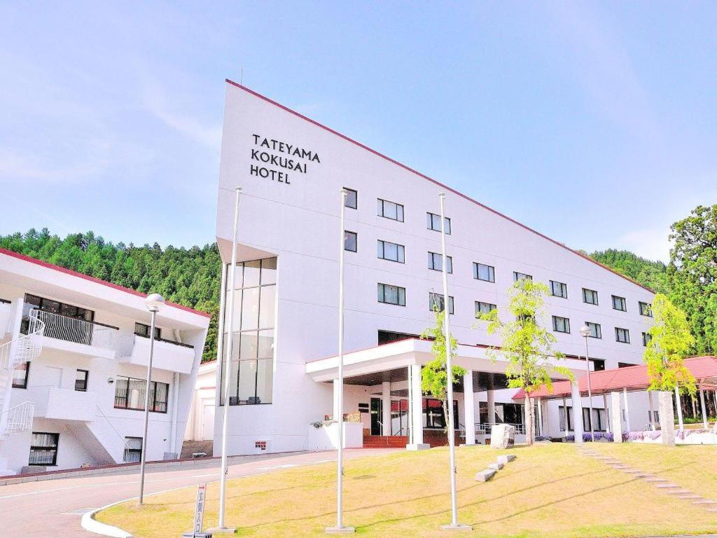 富山Tateyama Kokusai Hotel的一栋白色建筑，侧面有一块招牌
