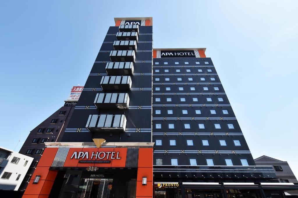 un grand bâtiment noir avec une enseigne d'hôtel dessus dans l'établissement APA Hotel Tsukuba Bampaku Kinenkoen Ekimae, à Tsukuba
