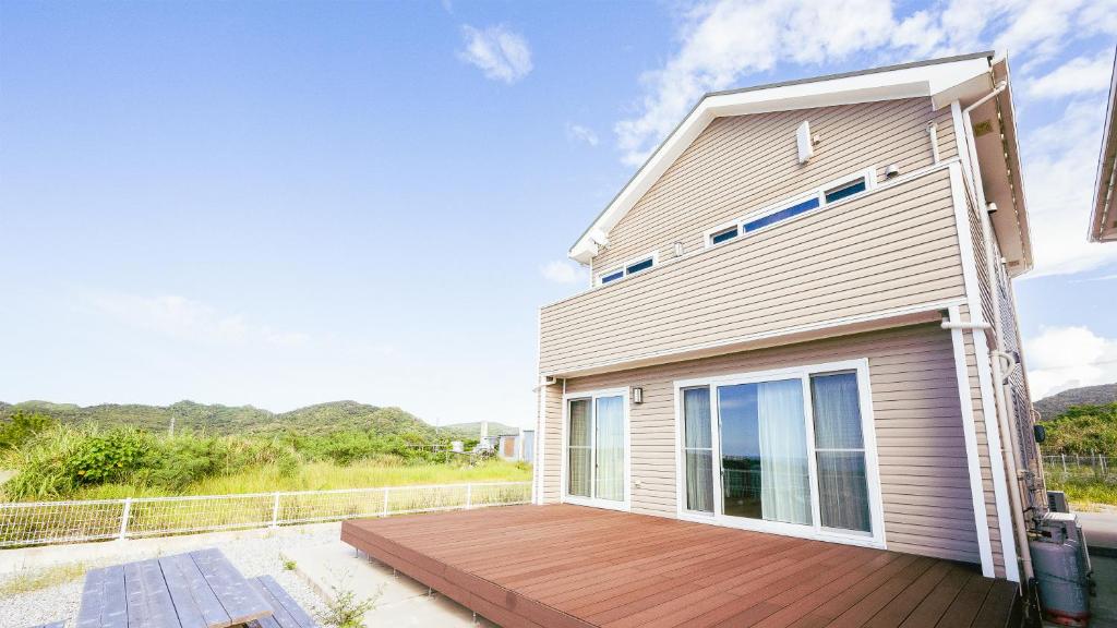 a house with a wooden deck in front of it at セイントS Saint-S in Motobu