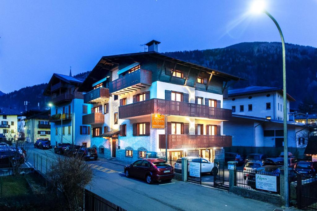 ein großes Gebäude mit davor geparkt in der Unterkunft Residence Alpen Casavacanze in Pinzolo