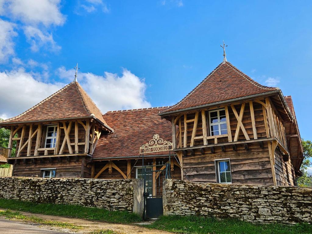 une grande maison en bois avec une clôture devant dans l'établissement Gîte du Château du Clos Voucheot, grand spa de nage, à La Bussière-sur-Ouche