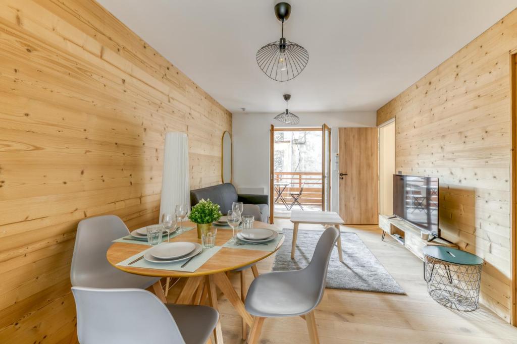 une salle à manger avec une table, des chaises et une télévision dans l'établissement Bergers - Calme - Chaleureux - Wifi - Vue, au Bourg-dʼOisans