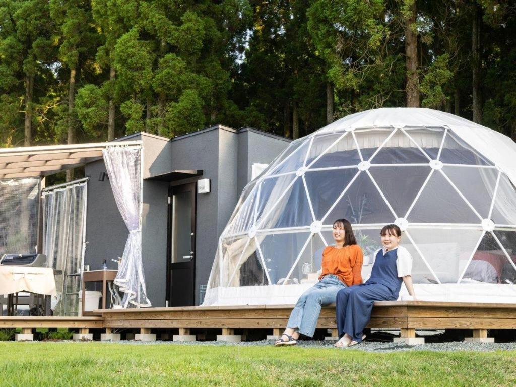 two women sitting on a bench in front of an igloo at Kosugi Resort in Aso