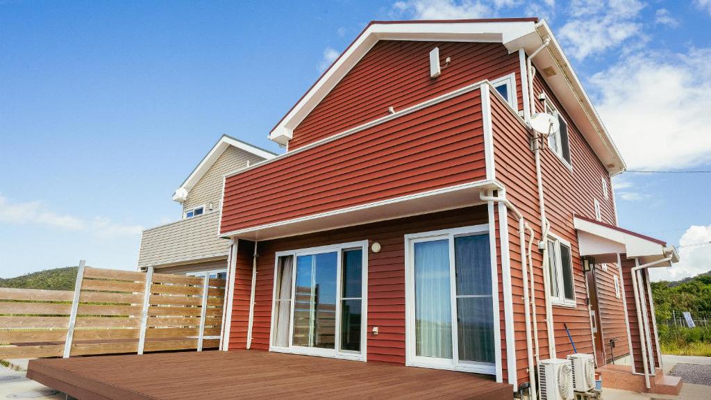 a red house with a wooden deck at セイントY saint-Y in Motobu